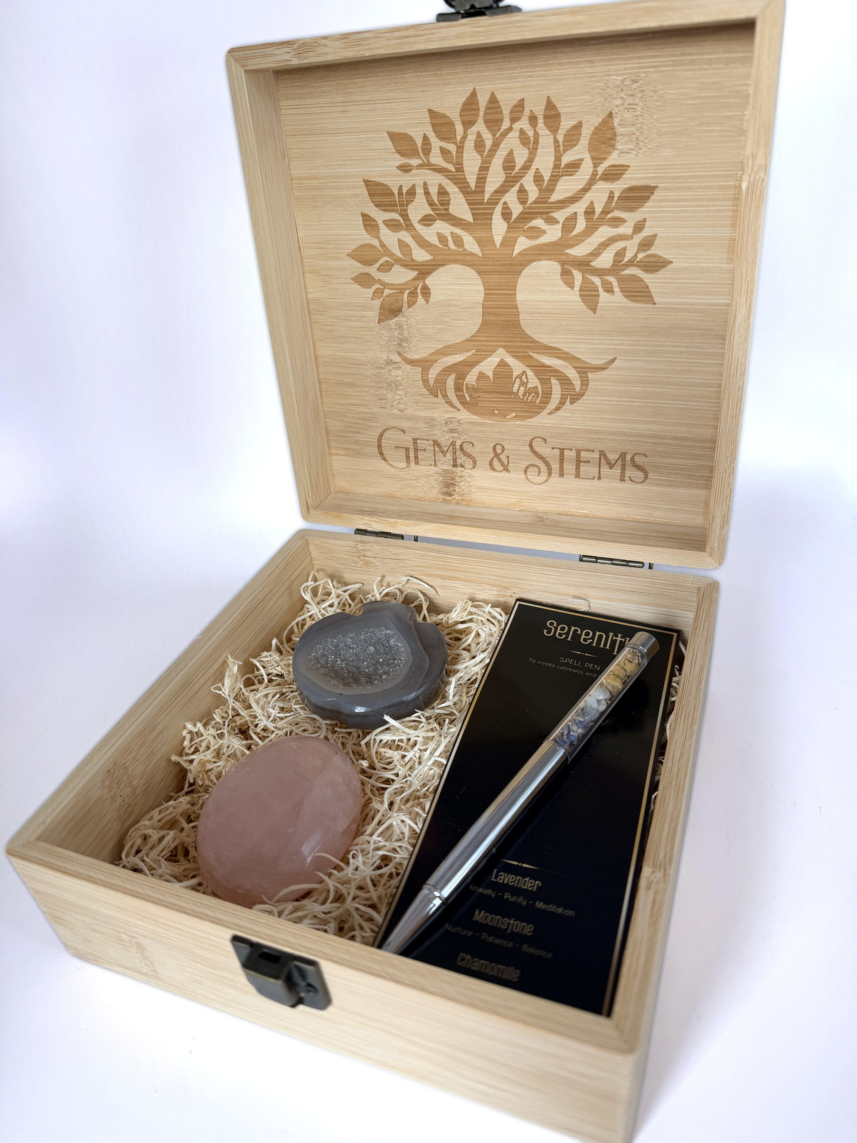 Bamboo keepsake box open showing an agate apple bowl, a rose quartz palm stone and a crystal pen