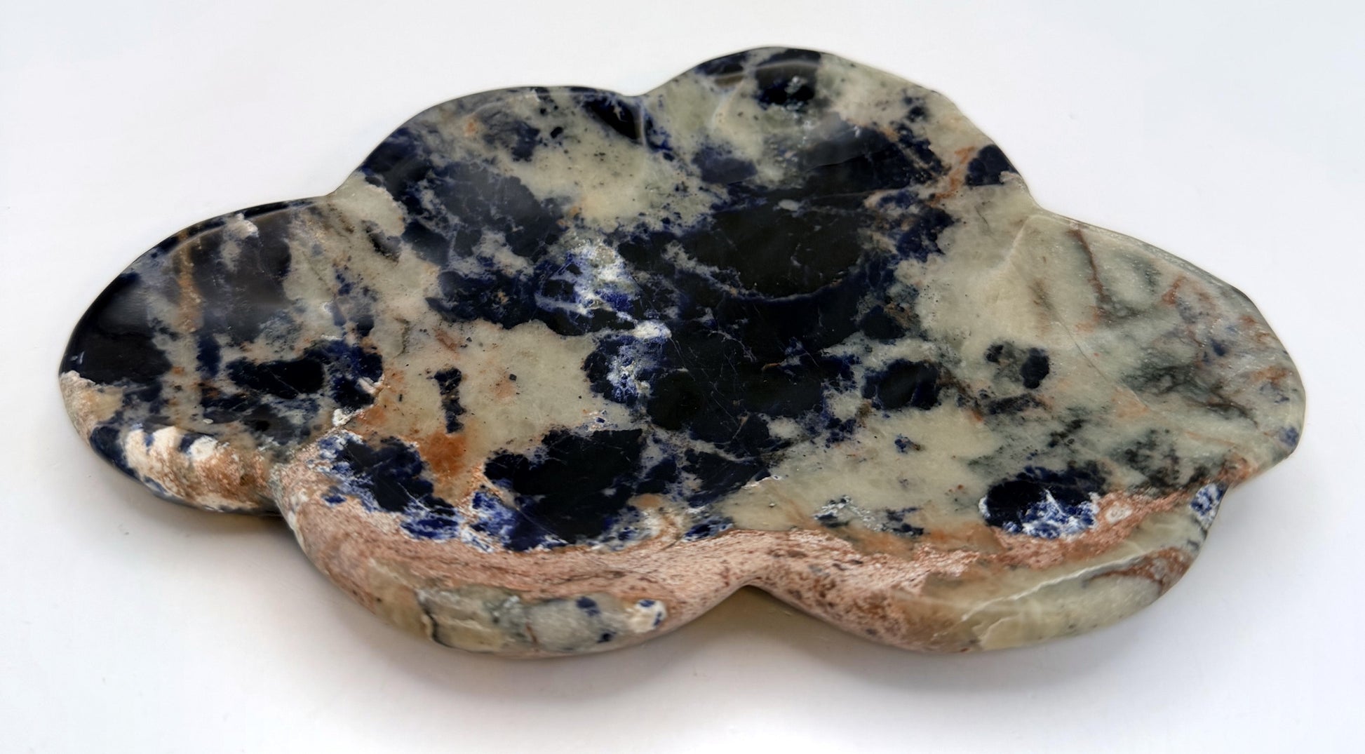 Angled view of the carved sodalite cloud dish showing the peach rim