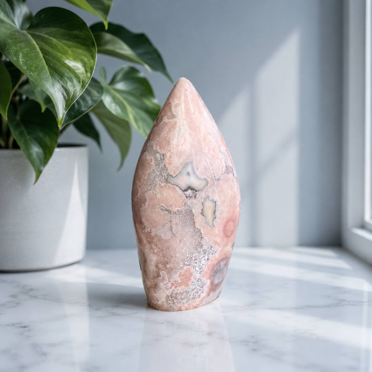 Pink Flower Agate flame styled on a marble windowsill beside a plant