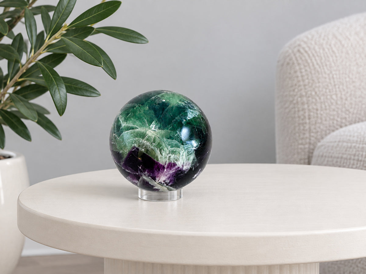 Rainbow fluorite sphere on its clear acrylic stand on a side table