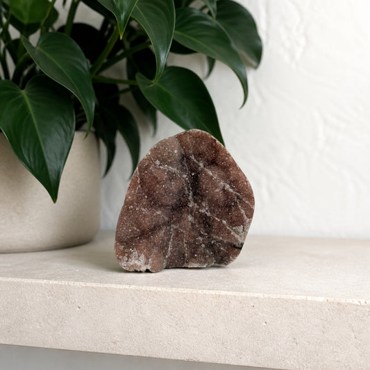 Rose druzy agate plate on a shelf