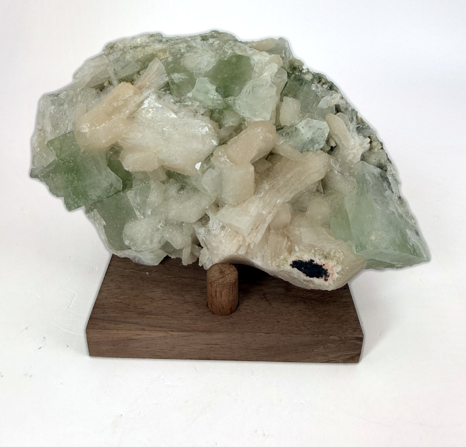 Green apophyllite with peach stilbite on a wood stand