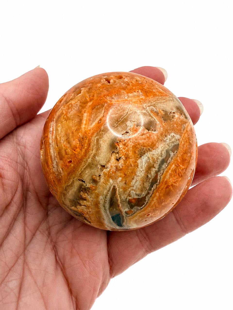 Lace Agate Crystal Sphere, hand held showing swirling orange banding