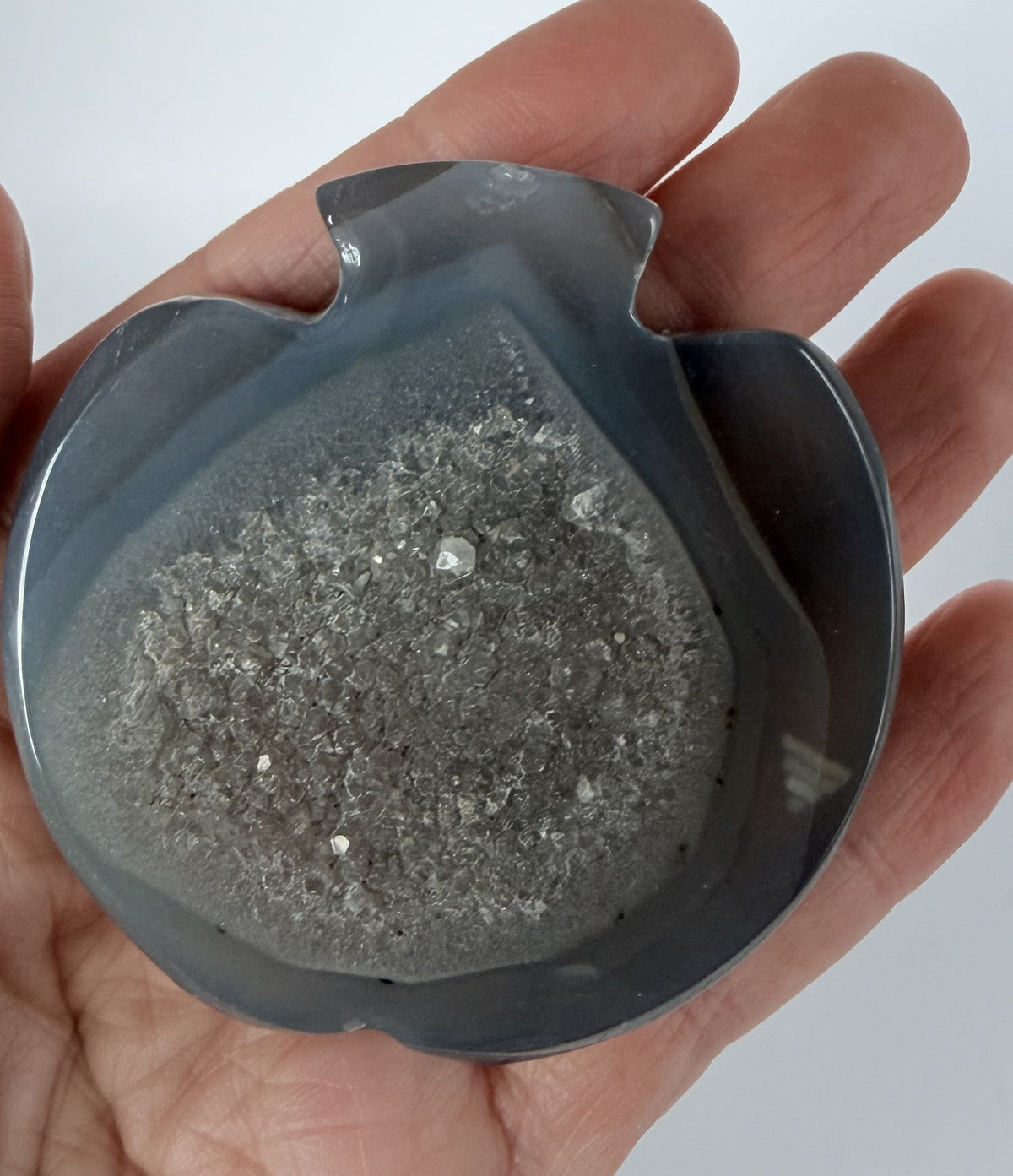 Grey agate apple bowl with a druzy quartz pocket held in a hand