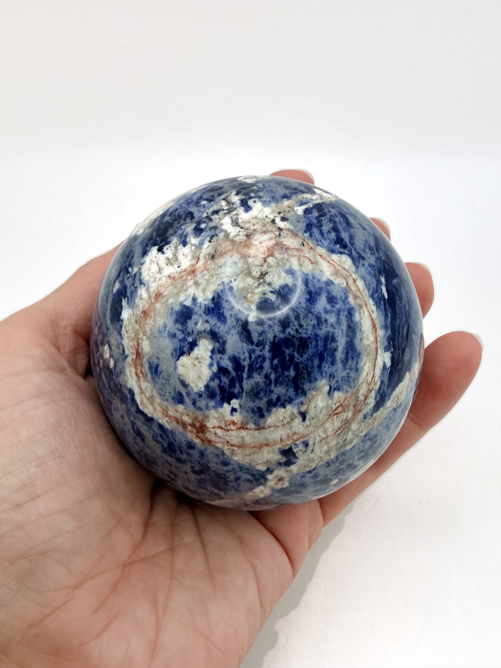 Sunset Sodalite sphere held in hand for scale