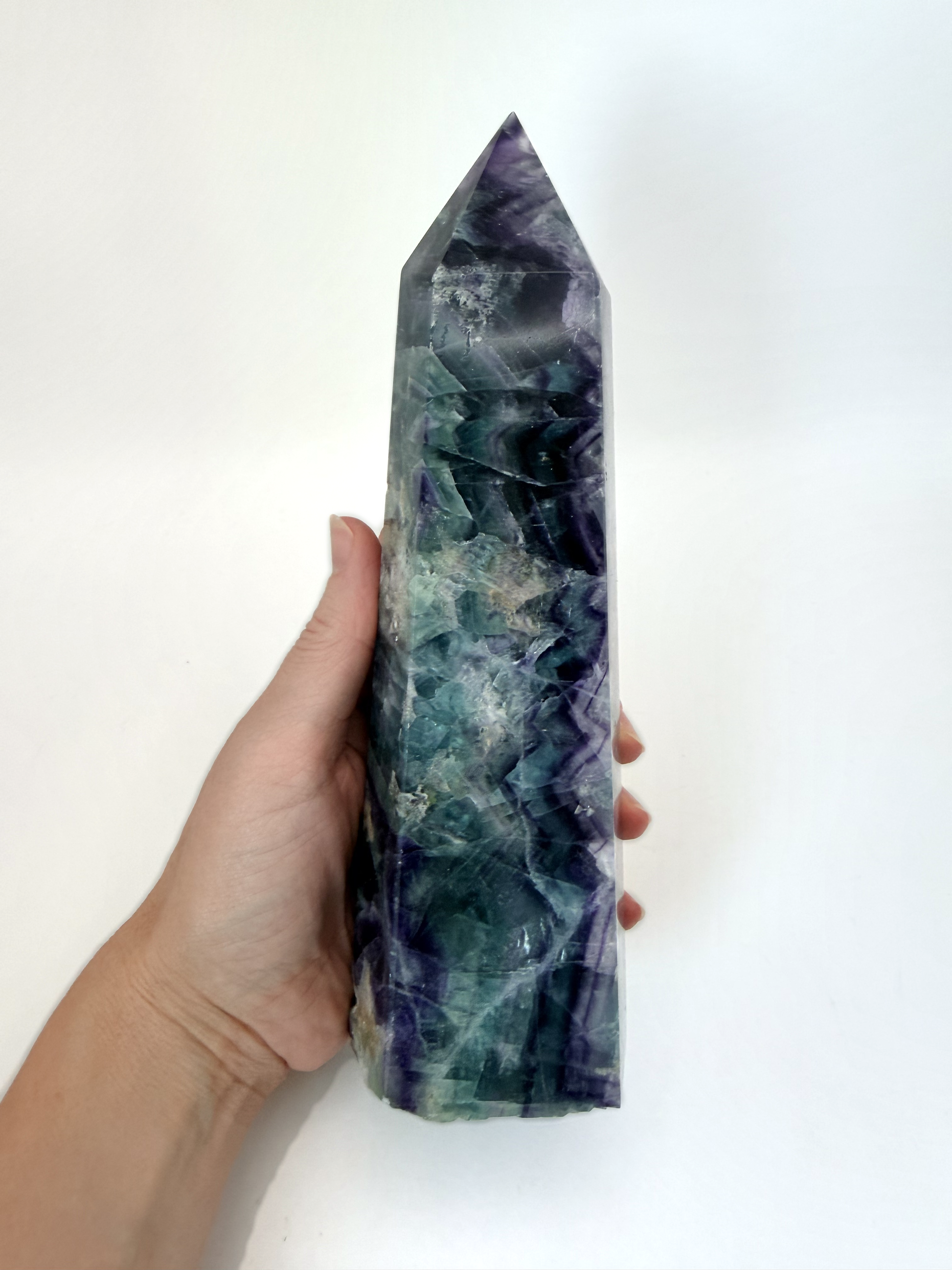 Rainbow fluorite tower held in hand for scale