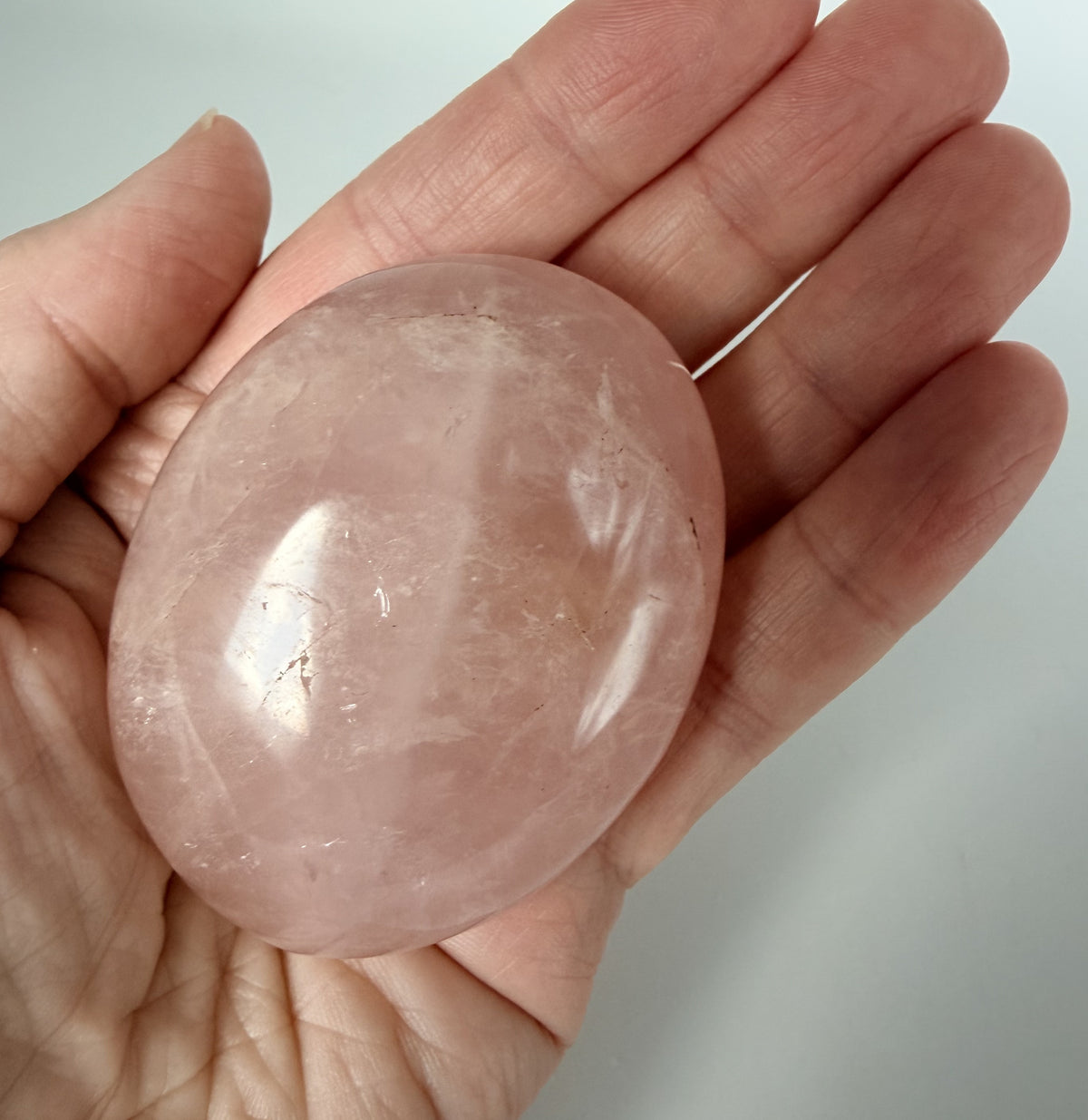 Rose quartz palm stone resting in an open hand