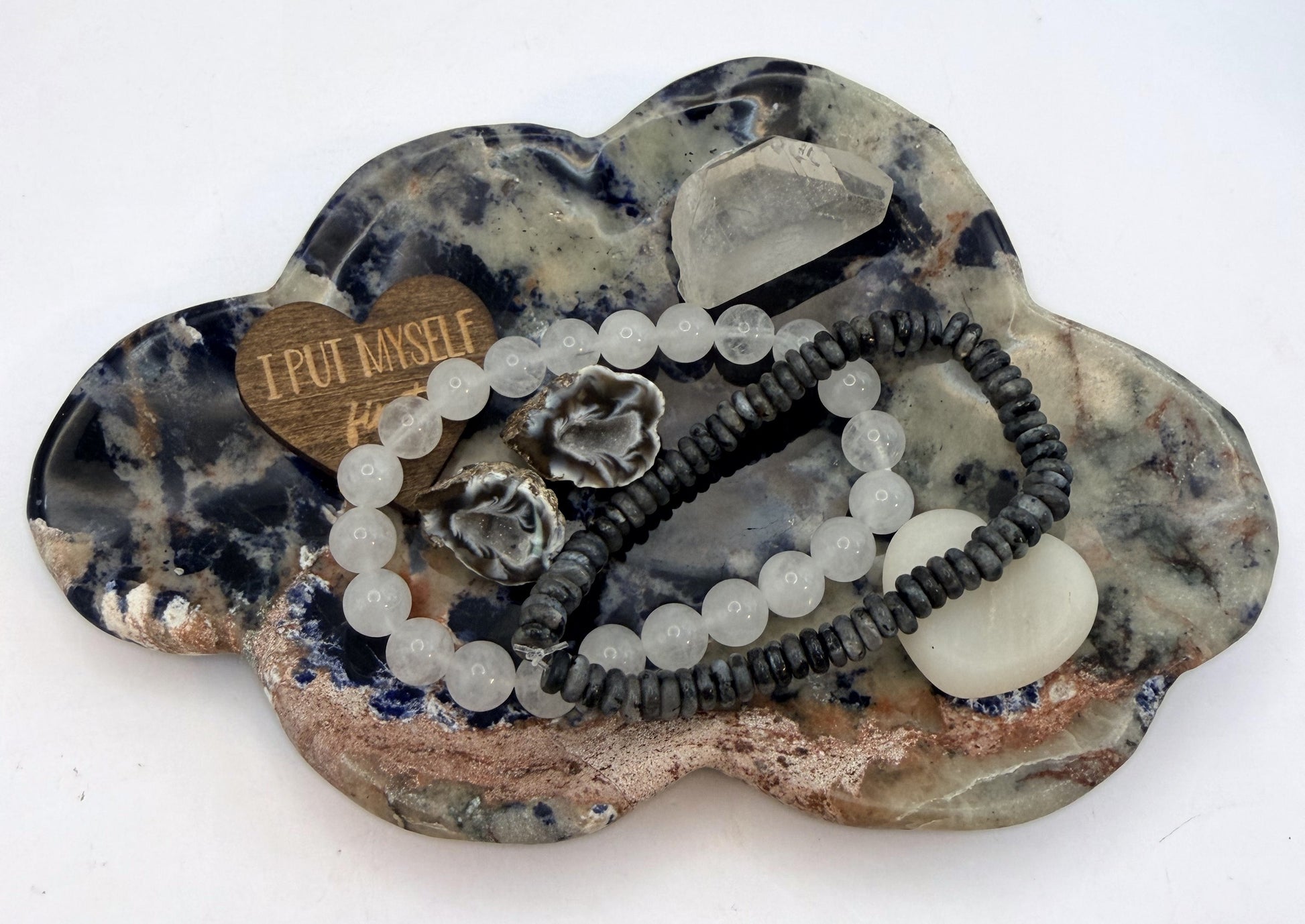 Sunset sodalite cloud dish holding bracelets and a quartz point