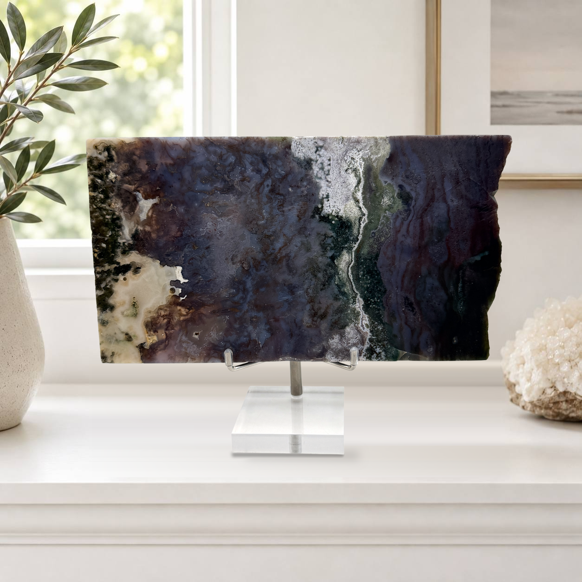 Purple moss agate slab on its acrylic stand on a bright mantel