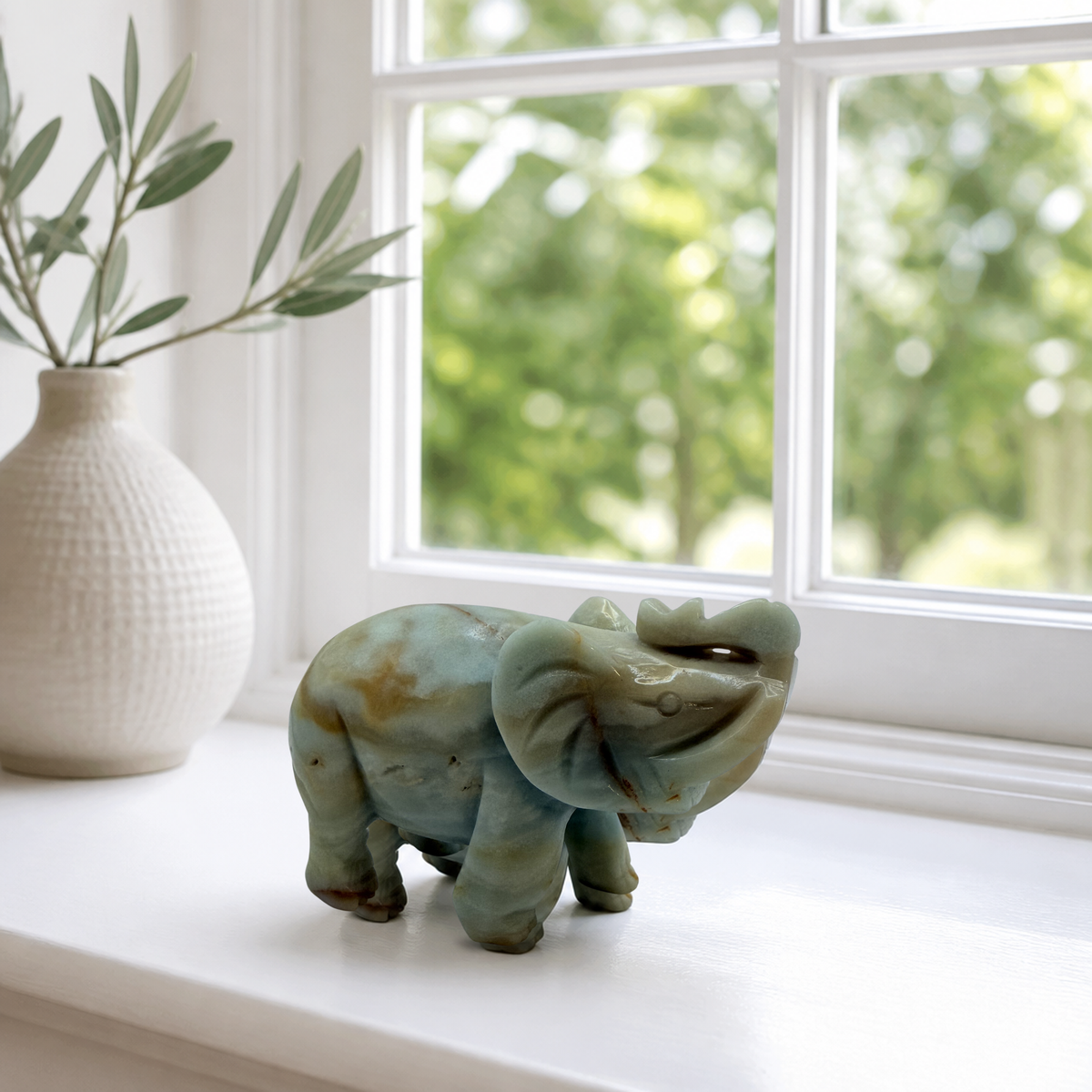 Carved banded calcite elephant on a bright white windowsill