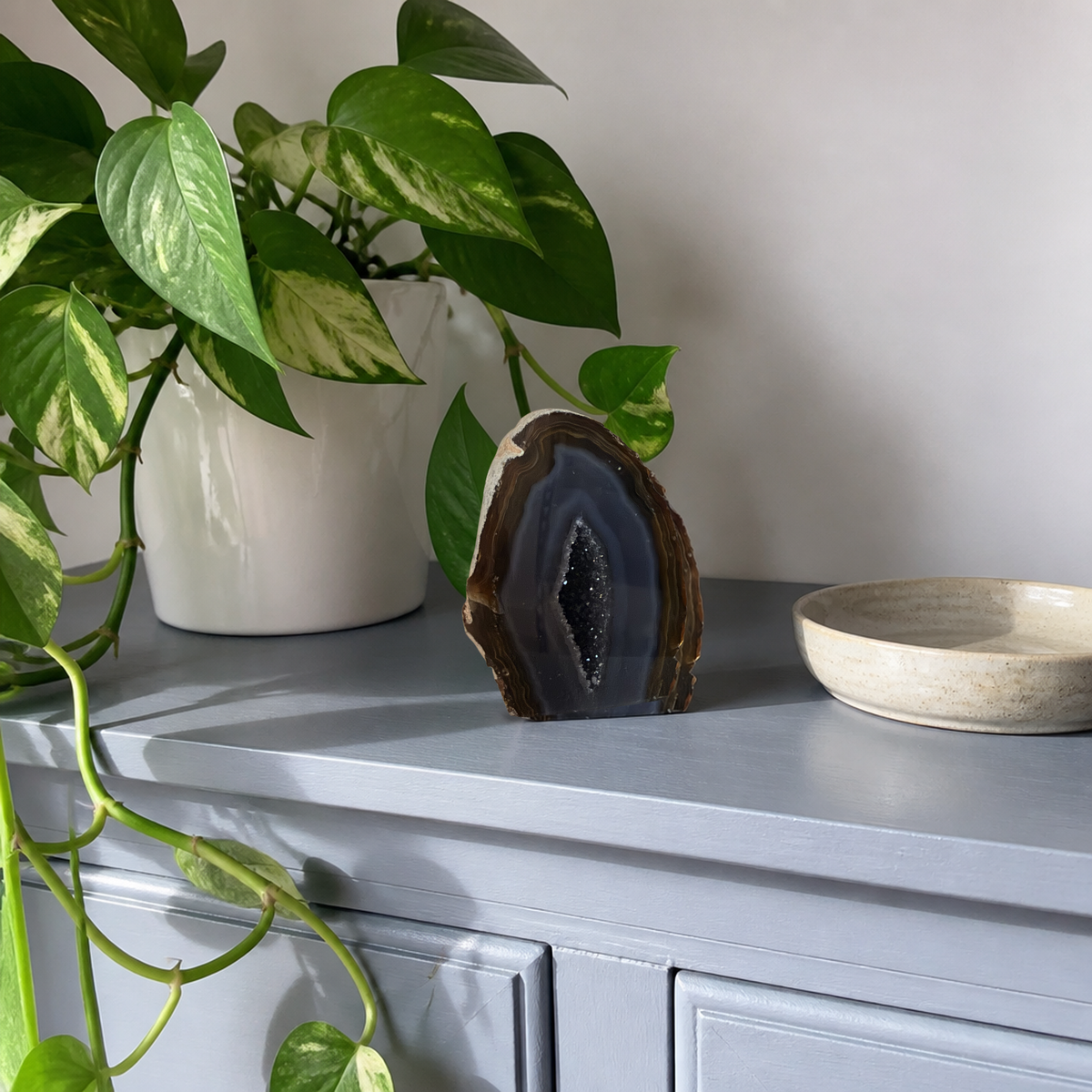 Banded agate geode on a slate blue cabinet in bright daylight