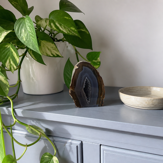 Banded agate geode on a slate blue cabinet in bright daylight