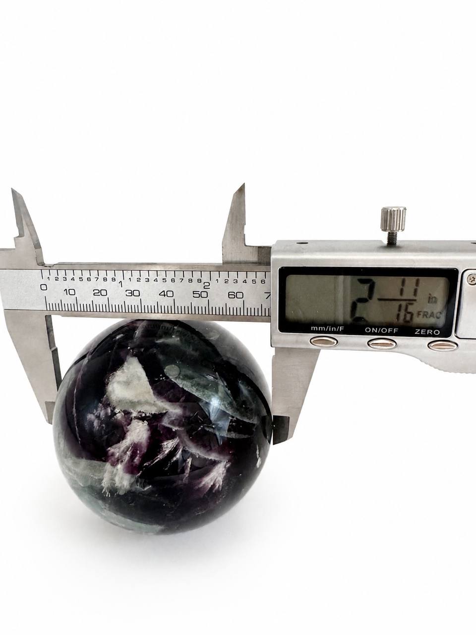 Rainbow fluorite sphere with caliper showing 2.11 inch diameter