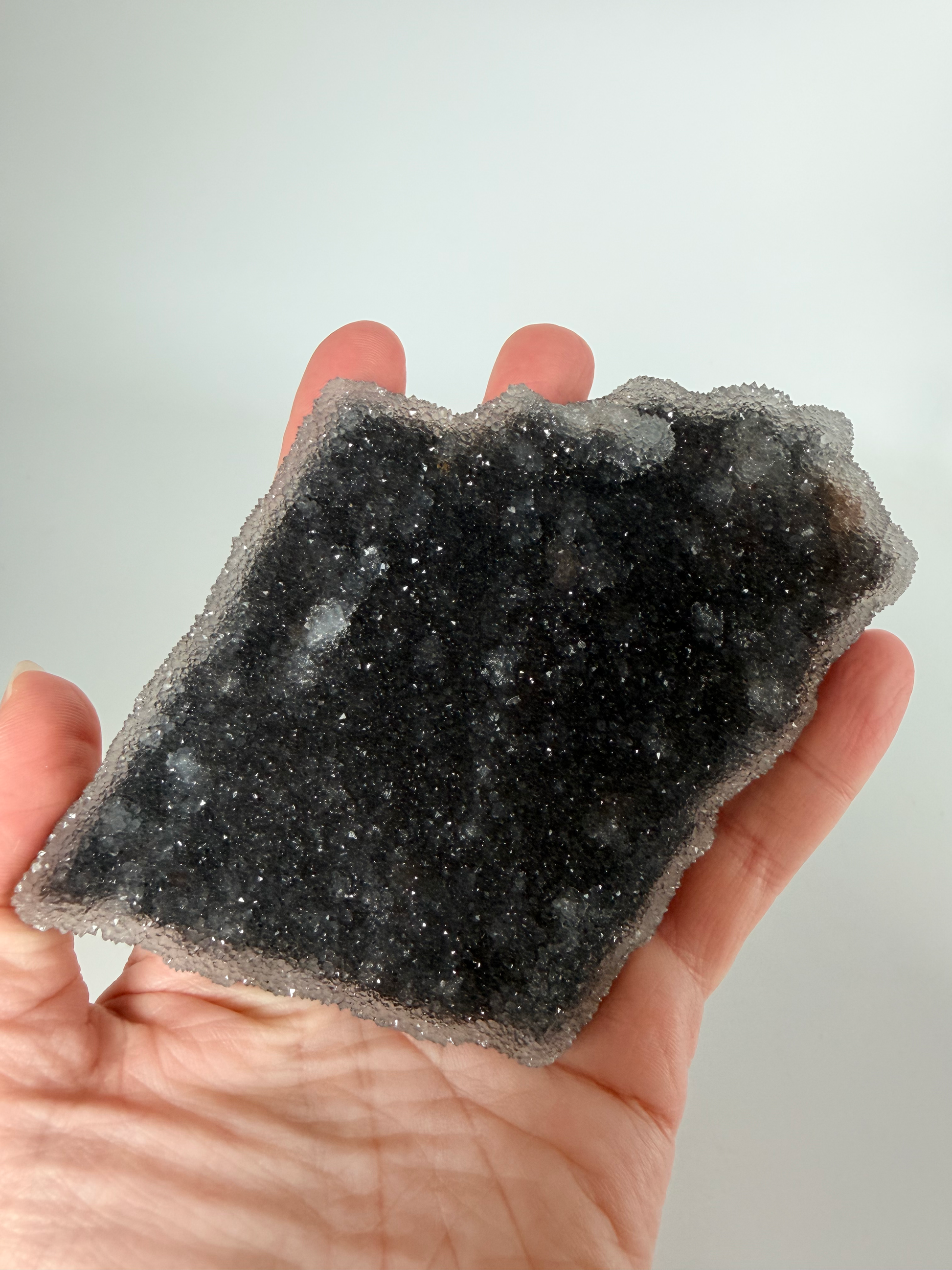 Amethyst druzy plate held in a hand for scale