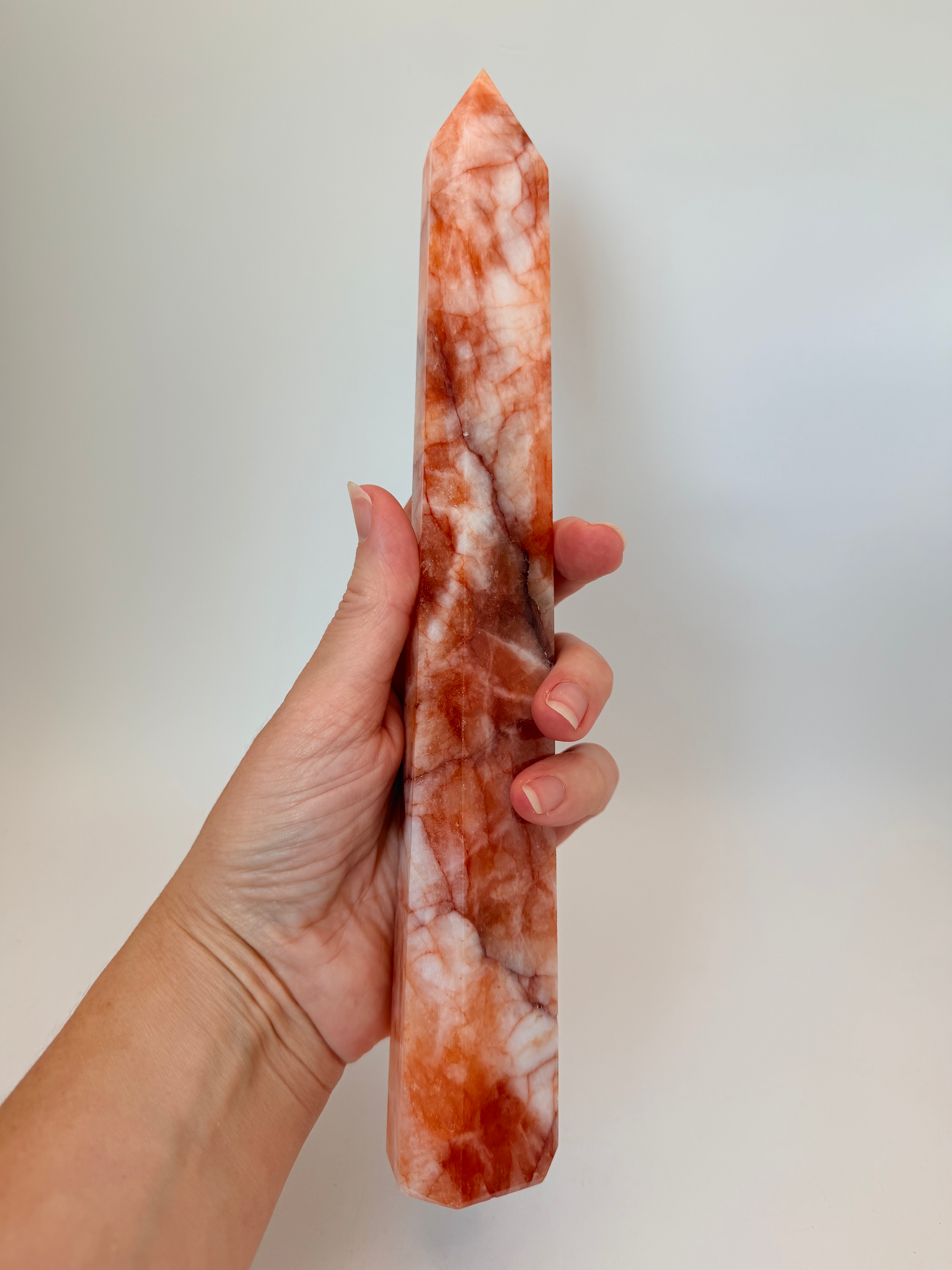 Fire quartz tower held in a hand for scale