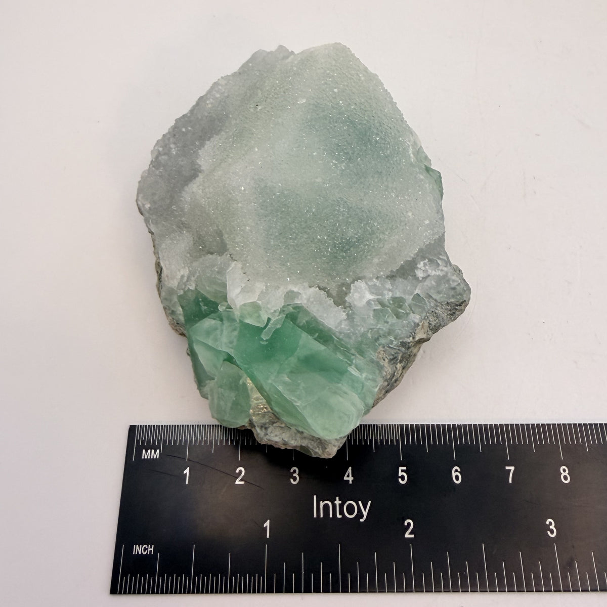 Green fluorite cluster with druzy quartz on a black display stand