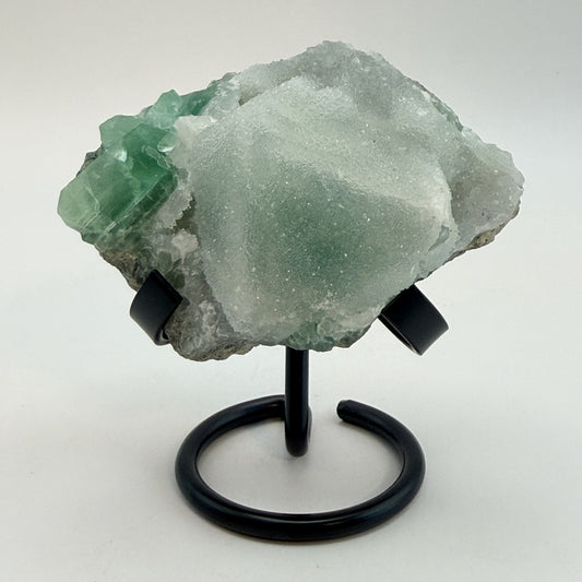 Green fluorite cluster with druzy quartz on a black display stand