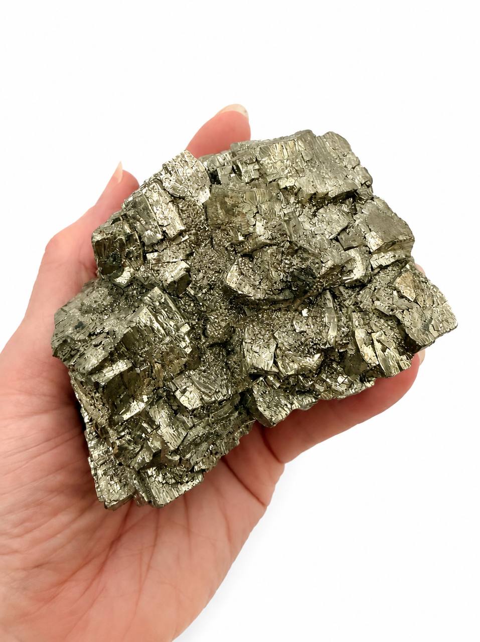 Pyrite crystal cluster held in hand showing cubic formations and scale