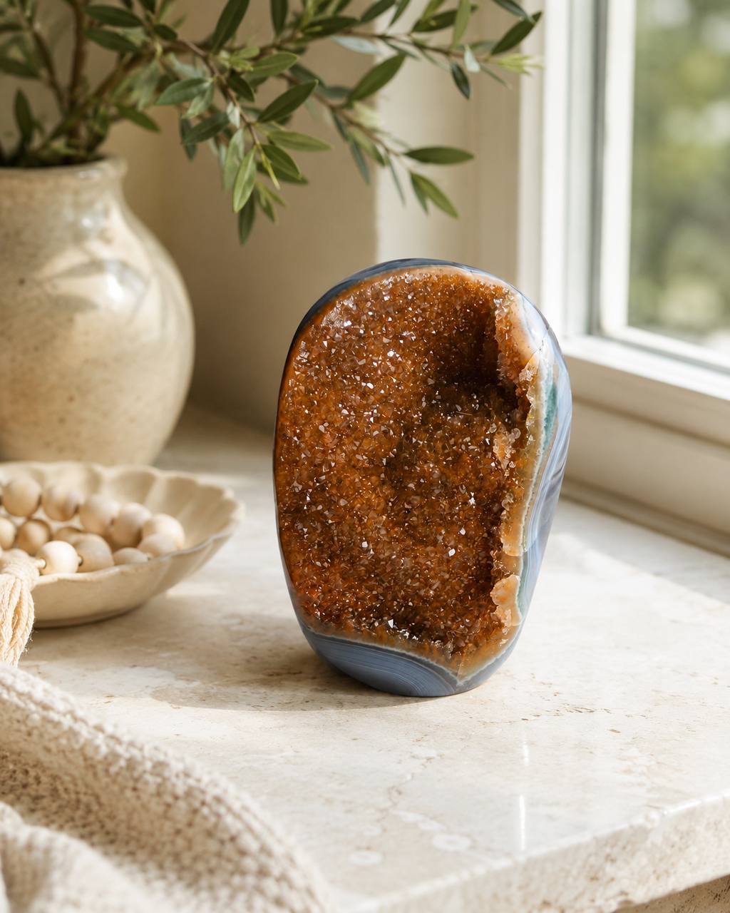 Polished agate freeform with citrine druzy on marble windowsill