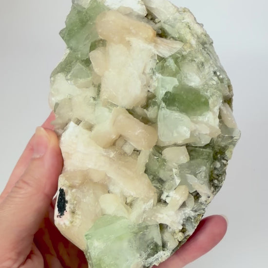 Green apophyllite with peach stilbite on a wood stand