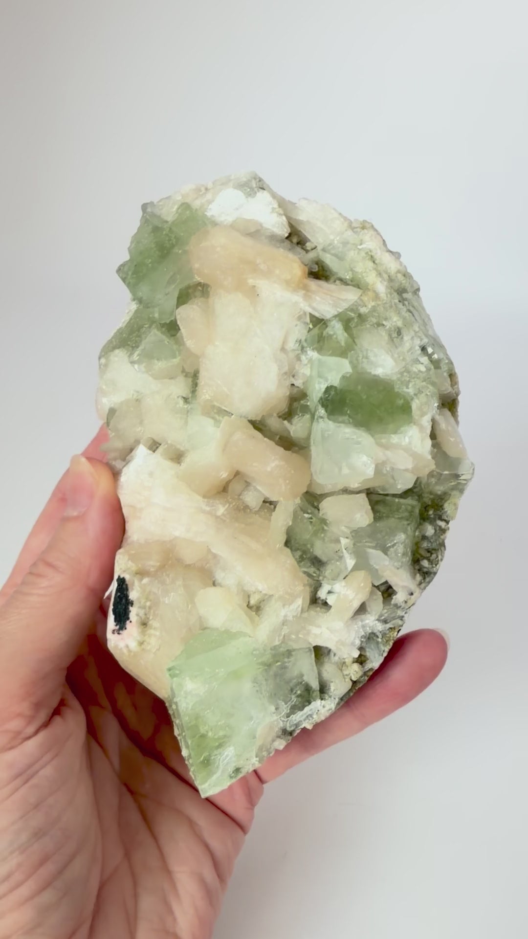 Green apophyllite with peach stilbite on a wood stand