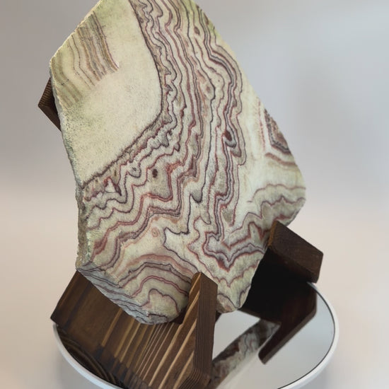 Banded calcite slab on wooden X stand