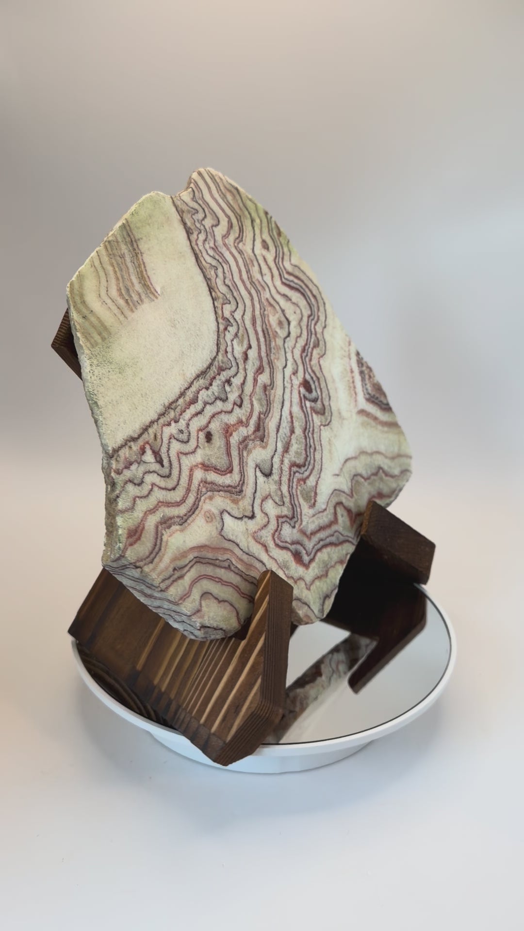 Banded calcite slab on wooden X stand