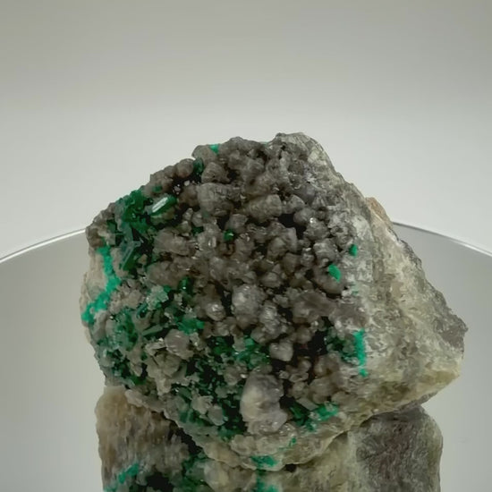 Dioptase on calcite cluster rotating on a mirrored display
