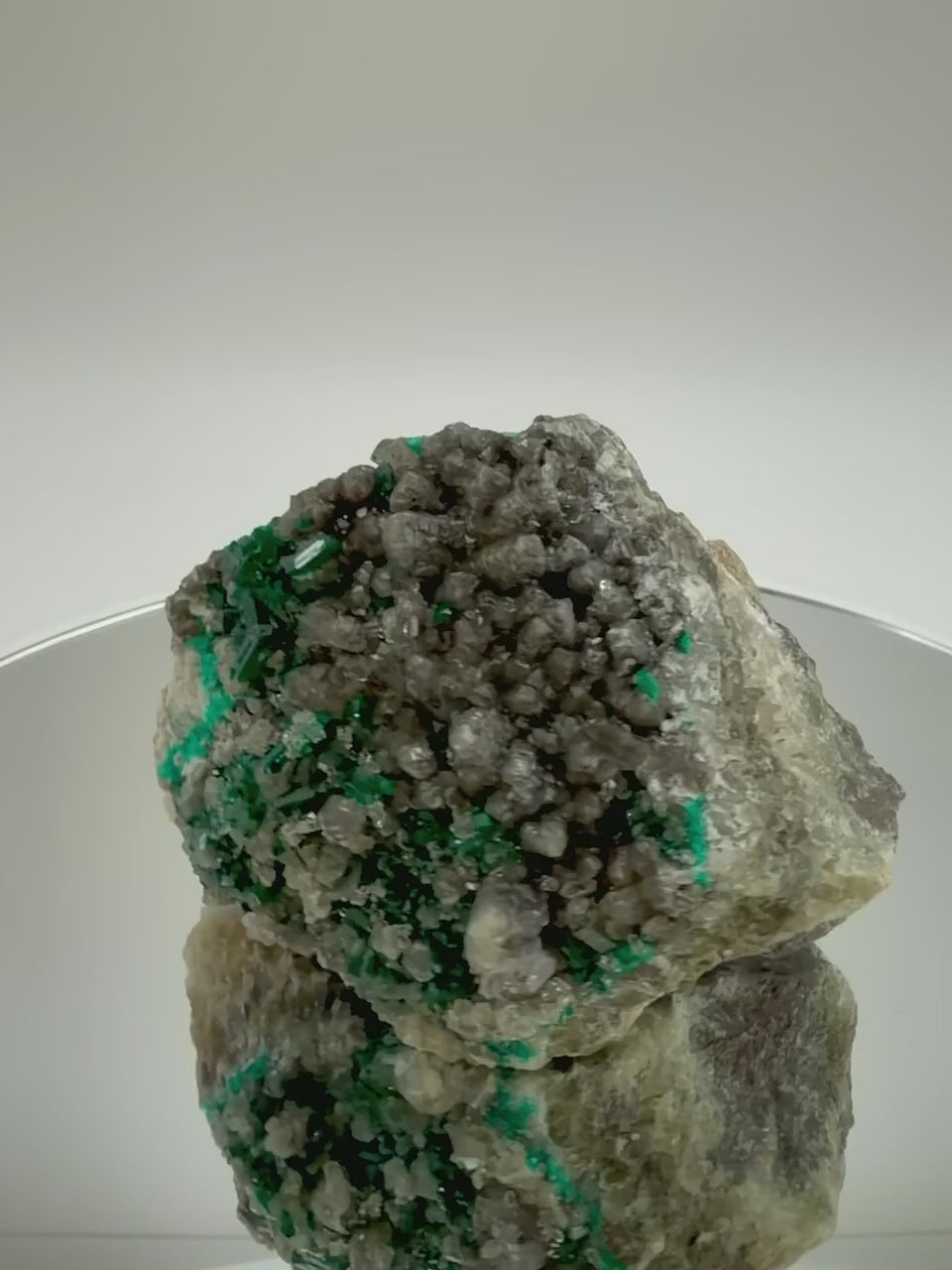 Dioptase on calcite cluster rotating on a mirrored display