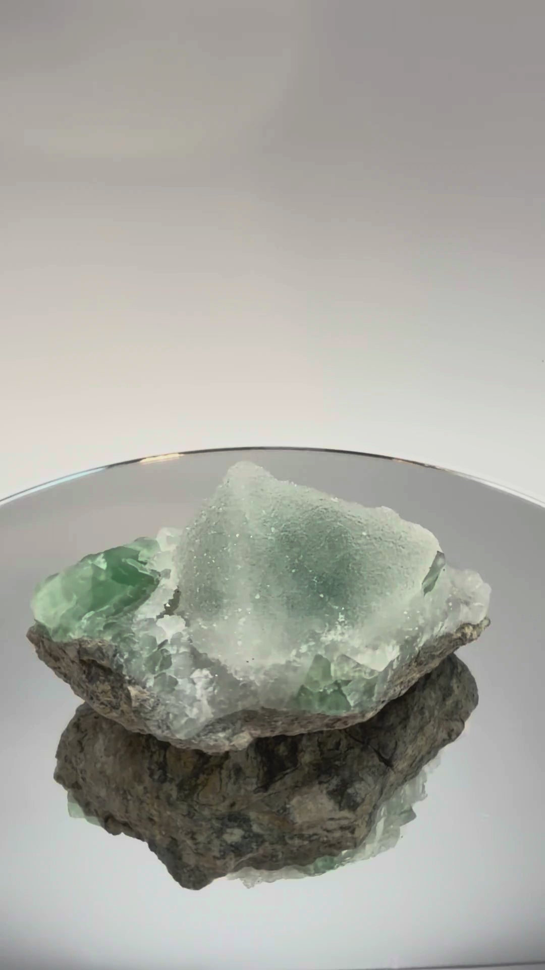 Green fluorite cluster with druzy quartz turning in the light