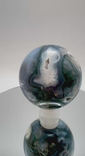 Moss agate sphere with druzy cavity rotating on stand
