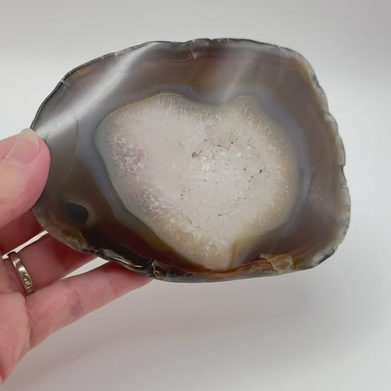 Natural agate slice with druzy quartz center and amber banding on acrylic stand