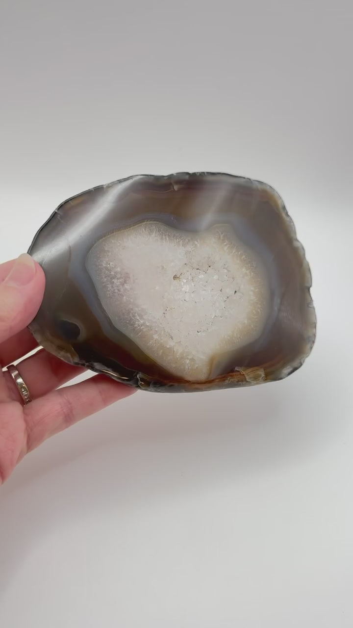 Natural agate slice with druzy quartz center and amber banding on acrylic stand