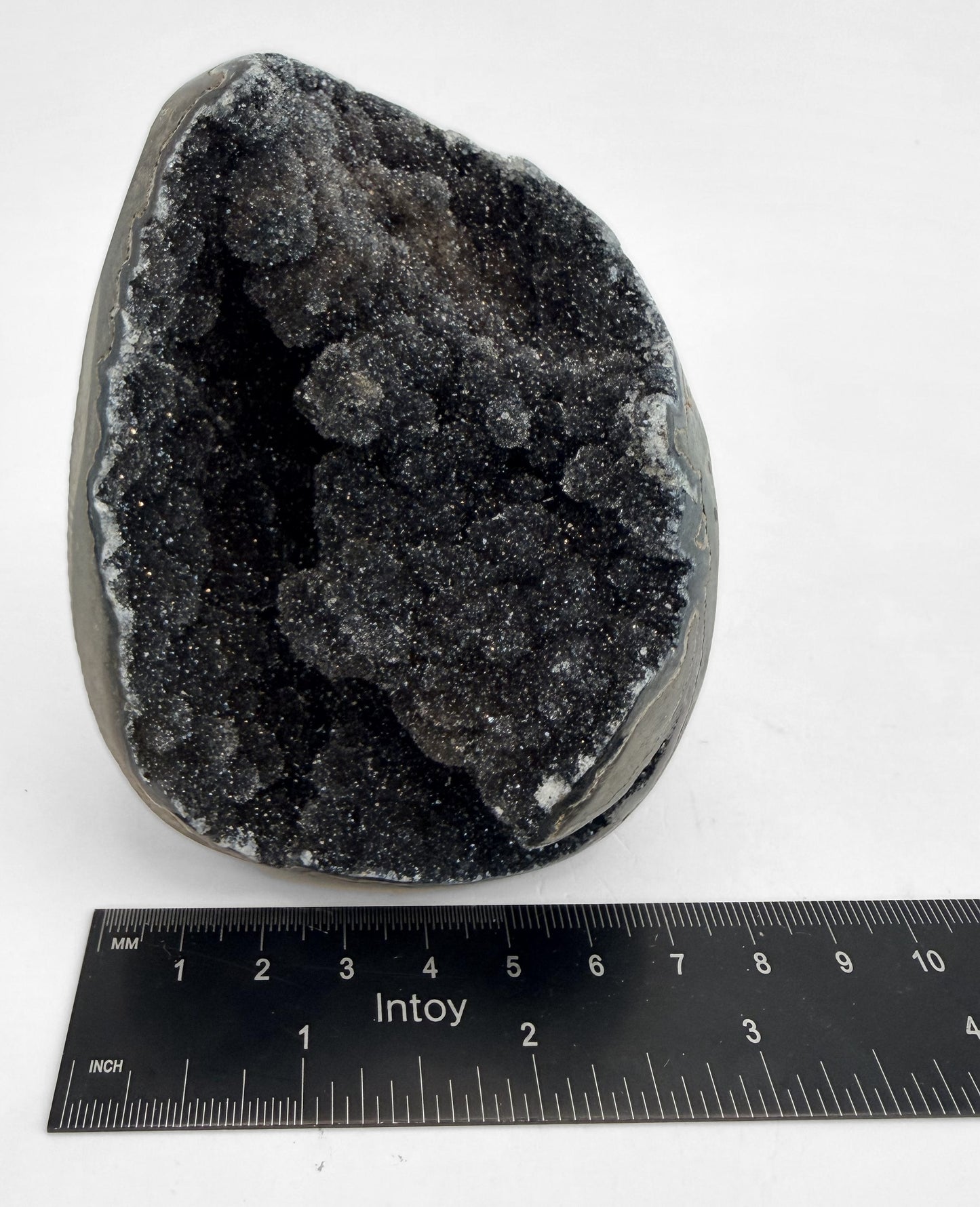 Druzy geode beside a steel ruler for width
