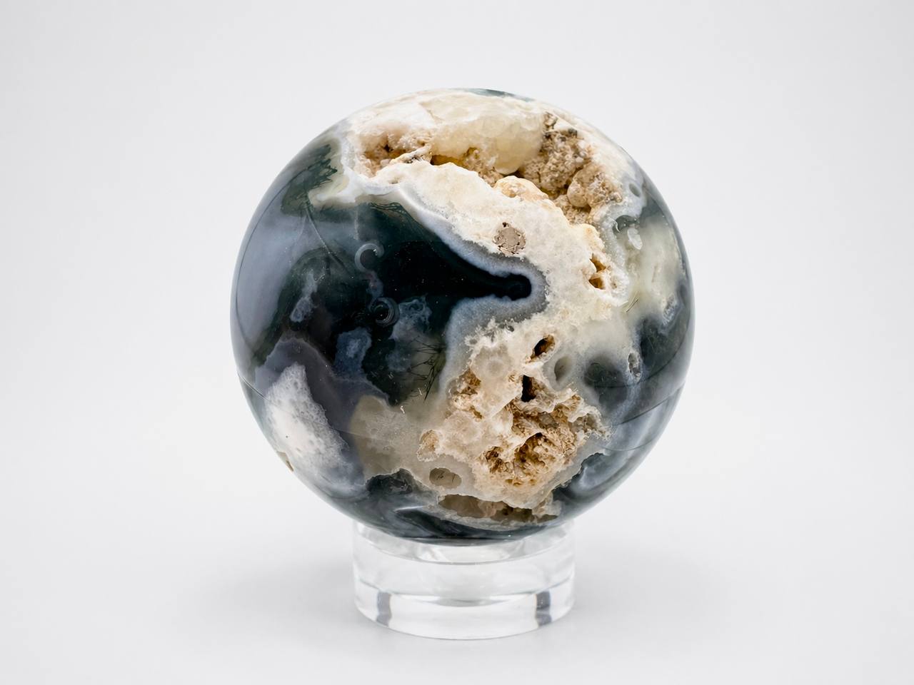 Moss agate sphere showing raw mineral cavity with cream formations