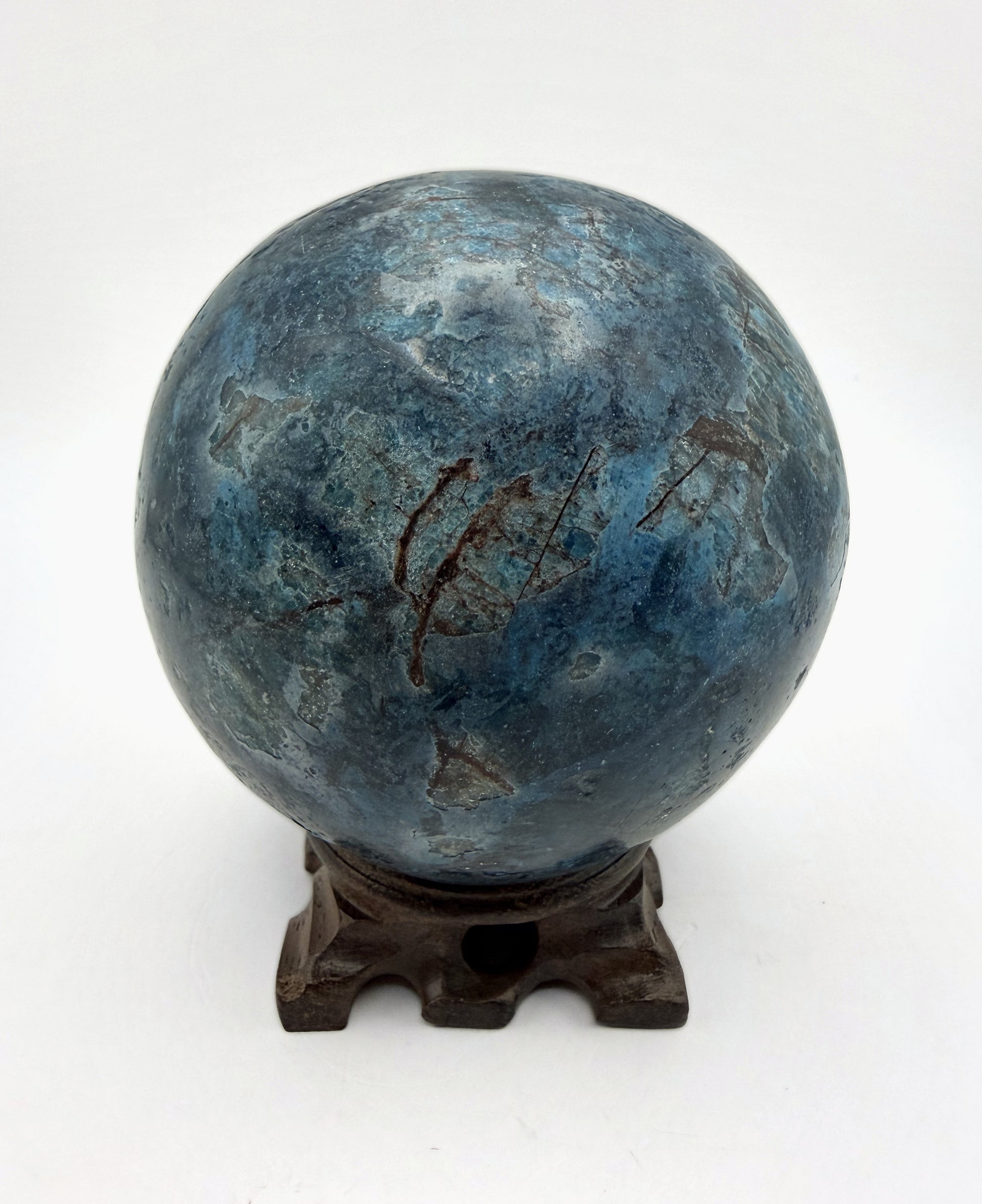 Blue apatite sphere on its carved wooden stand