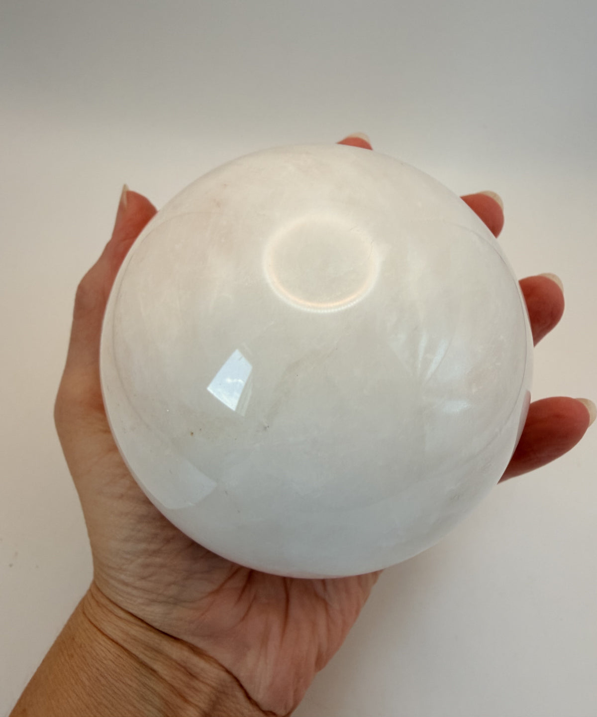 Milky quartz sphere held in hand