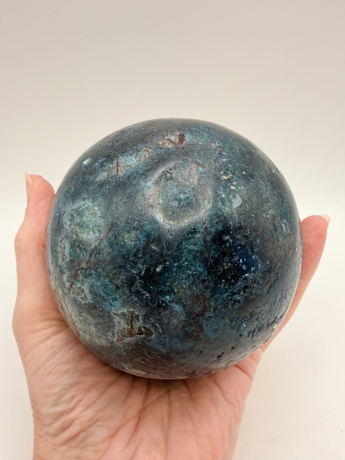 Blue apatite sphere held in hand