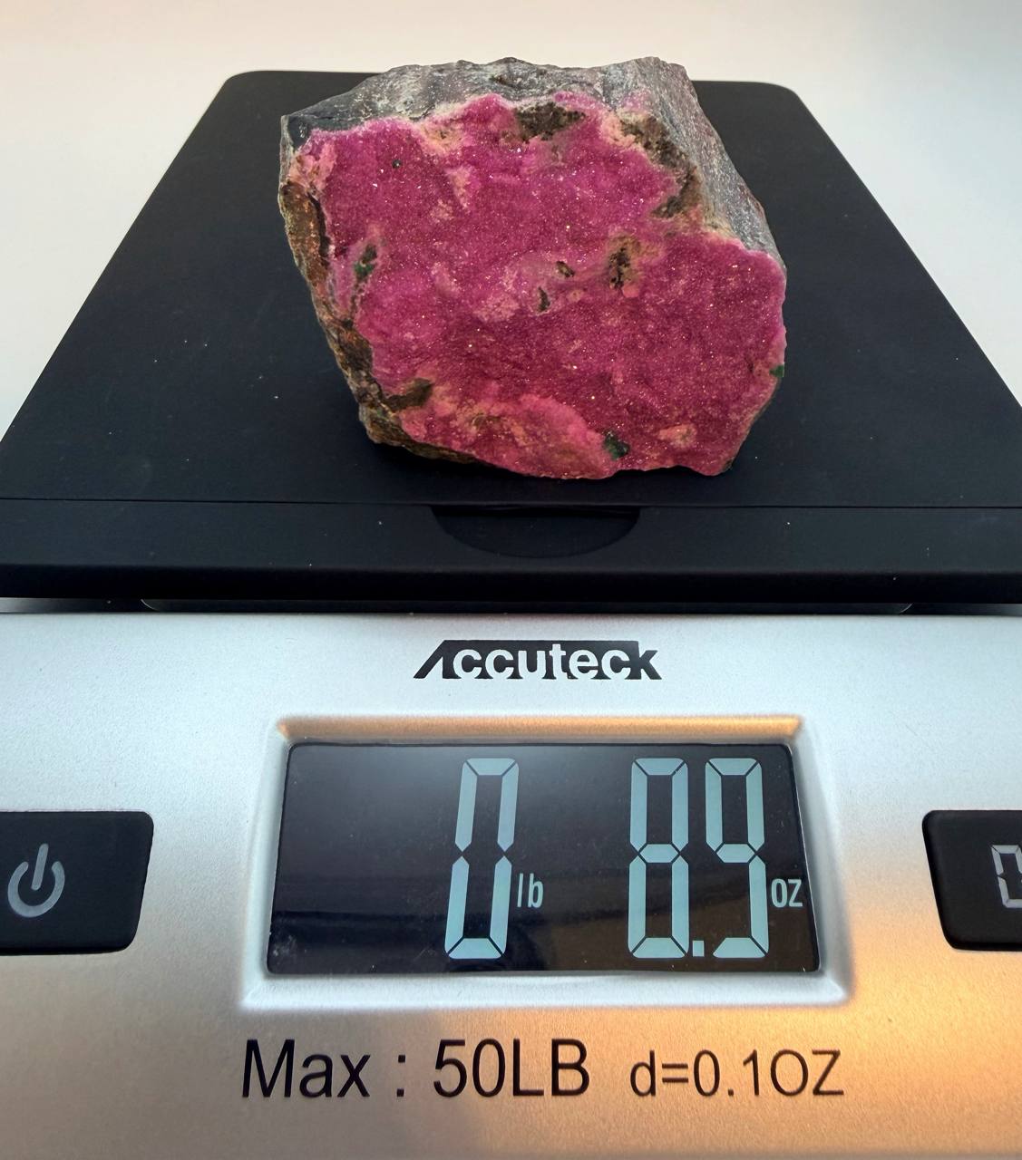 Pink cobaltoan calcite on scale showing 0 lb 8.9 oz
