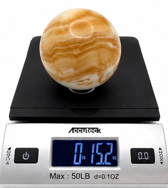Honey calcite sphere on scale showing 15.2 oz